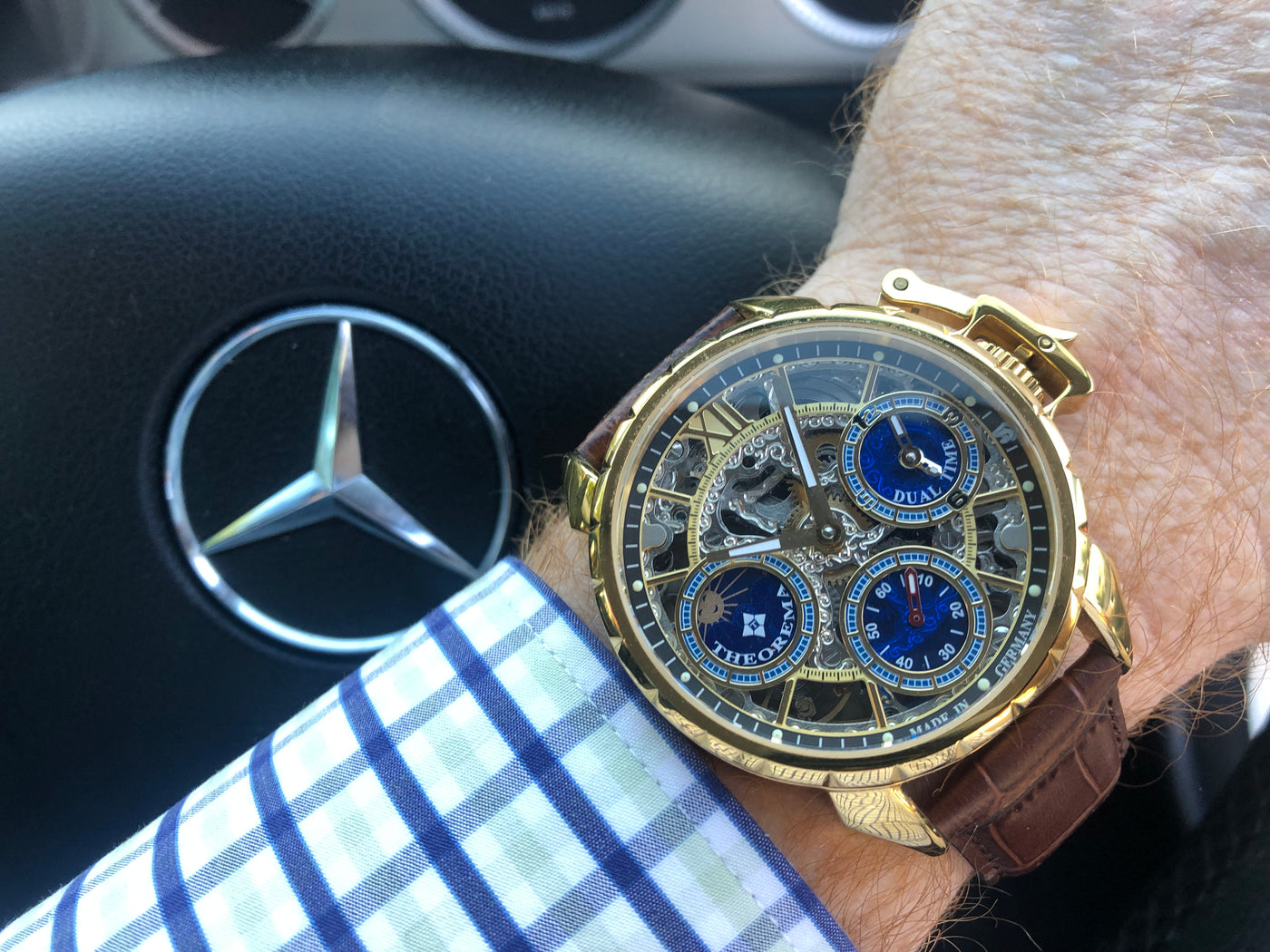 wrist shot photo of golden watch with skeletonize design and the Mercedes-Benz car logo